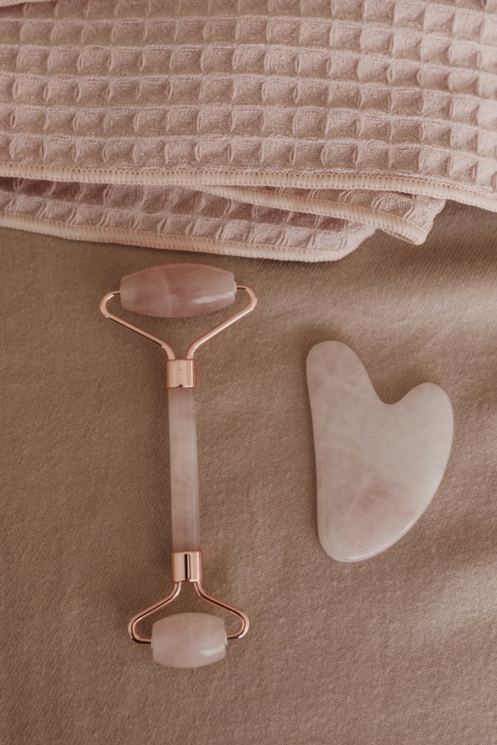 Flat lay of a rose quartz skincare tool set and towels for a wellness routine.